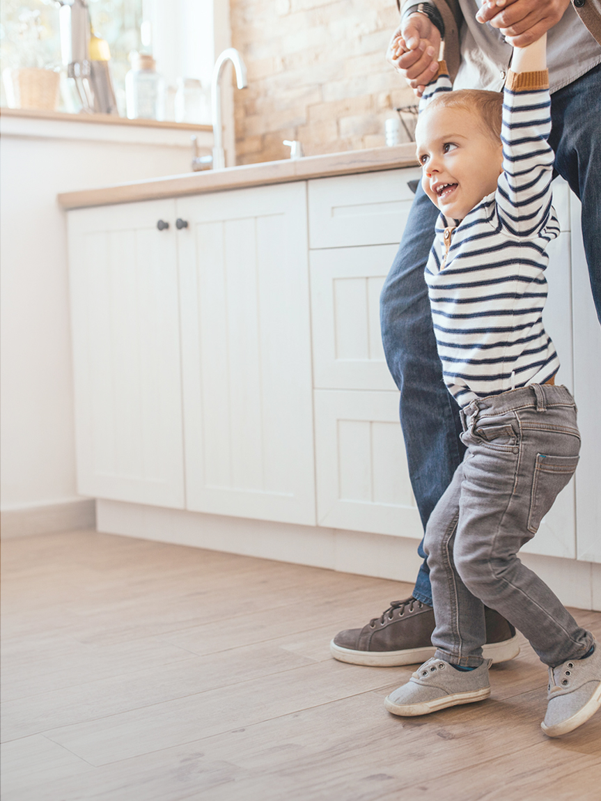 Woman sitting on a hardwood floor with a coffee mug in her hand.